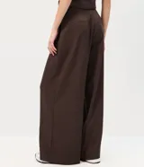 Pantalón sastrero de corte amplio y tiro alto, color marrón, con pinzas frontales profundas y cierre lateral con botón en la pretina.
