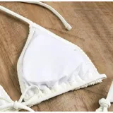 Conjunto de baño de cuatro piezas en color negro, confeccionado en tejido de malla transparente. Incluye un top de bikini triangular, una remera manga larga abierta con lazo frontal para anudar, y una pollera corta ajustable con cordones laterales.