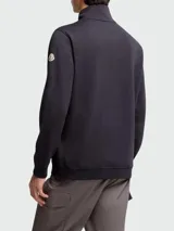Buzo de algodón color negro con capucha integrada, cierre frontal parcial con cremallera y detalle de cinta tricolor. Presenta una capa interior en color verde con puños y ruedo elásticos, y el logo de la marca bordado en el pecho.