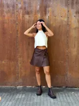 Minifalda tipo pareo confeccionada en cuero color chocolate, con diseño cruzado y cierre mediante tiritas laterales ajustables.