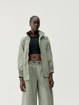 Chaqueta cortaviento verde oliva, de tejido técnico Wind_S, con cuello alto, cierre frontal y puños ajustables. Presenta un calce holgado y bolsillos con cremallera.