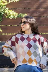 Sweater tejido de algodón con diseño de rombos multicolor en tonos bordó, mostaza, verde oliva y beige. Presenta una silueta oversize, cuello redondo y mangas largas abullonadas con puños ajustados.