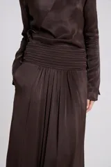 Pollera maxi evasé de tejido satinado en color marrón, con detalle de frunces en la cintura.