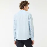 Camisa de manga larga celeste con estampado de pequeños lunares oscuros, corte regular, cuello camisero clásico y cierre frontal de botones.