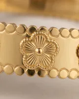 Esclava rígida de acero con baño de oro, con diseño de flores grabadas en relieve a lo largo de toda la pieza.