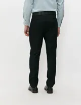 Ambo negro de corte clásico para hombre, compuesto por saco de solapas de muesca con dos botones, chaleco abotonado a juego y pantalón de vestir de corte recto.
