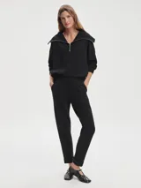 Pantalón negro de tejido DoubleSoft, corte ajustado con puños enrollados, pinzas delanteras y traseras, y bolsillos con forma.