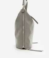 Bolso grande tipo hobo desestructurado, color gris claro con acabado ligeramente brillante o envejecido. Cuenta con dos asas cortas y una correa larga desmontable. Presenta detalles de cierres o tiradores decorativos en los laterales y cierre principal superior con cremallera.