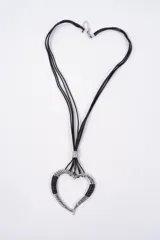 Collar con dije de corazón plateado, con detalles de textura trenzada y secciones en cuero negro, suspendido de múltiples cordones negros finos.