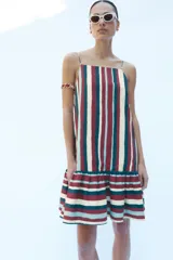 Vestido mini confeccionado en hilatura con lino, de escote recto con tirantes finos ajustables y bajo acabado con volantes, con diseño de rayas verticales en la parte superior y horizontales en el volante.