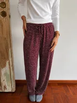 Pantalón tipo pijama bordó con estampado de pequeños puntos blancos, corte holgado, cintura elástica con cordón de ajuste y bolsillos laterales.