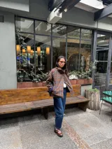 Campera reversible de corte amplio y cuello alto. Un lado presenta un diseño a cuadros en tonos marrones y azules, mientras que el otro lado es de color azul liso. Cuenta con cierre frontal de botones y mangas largas.