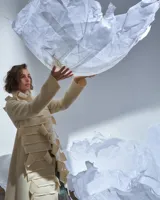 Tapado largo color natural de lana merino afieltrada, con cuello grande formado por piezas horizontales. Tiene bolsillos laterales y se puede usar suelto o cerrado con un accesorio.