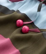 Vestido midi con estampado abstracto en tonos rosa, marrón, verde y celeste. Tiene escote en V, mangas cortas tipo murciélago y lazo ajustable en la cintura.