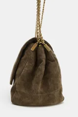 Bolso de hombro confeccionado en piel de ante, con diseño estructurado y solapa frontal con cierre imantado. Presenta pespuntes decorativos en el cuerpo y una correa combinada de cadena metálica dorada y piel.