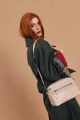 Bandolera de diseño moderno y funcional, confeccionada en nylon color marrón claro. Cuenta con múltiples compartimentos con cierre metálico, herrajes plateados y una correa ancha ajustable con detalle de marca.