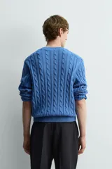 Jersey de punto de algodón, color azul, con cuello redondo y manga larga. Presenta un tejido con estructura de trenzas verticales a lo largo de todo el cuerpo y mangas.