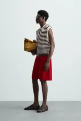 Camiseta sin mangas de punto con cuello redondo, tejido abierto a rayas horizontales negras y blancas, con ribetes en color crema.