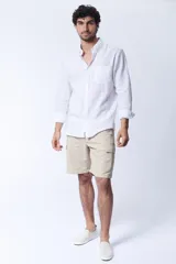 Camisa blanca de lino, de corte clásico, con cuello abotonado, manga larga con puños abotonados y bolsillo en el pecho.