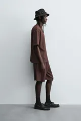 Camiseta de algodón de corte relajado (relaxed fit) color marrón oscuro, con cuello redondo y manga corta. Presenta una textura acanalada vertical tipo jacquard.