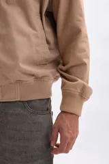 Campera estilo bomber de hombre, color tostado, con cierre frontal metálico, cuello y puños acanalados.