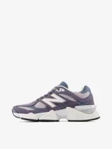 Championes urbanos New Balance serie 9060, con diseño robusto en tonos gris y violeta. Confeccionados en una combinación de gamuza, malla y materiales sintéticos. Presentan una entresuela gruesa con tecnología ABZORB para una amortiguación superior y suela de goma con excelente tracción.