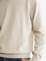 Sweater de algodón color beige, de cuello redondo y corte clásico. Presenta el logo de la marca bordado en el pecho.