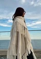 Ruana color crudo de tejido artesanal en telar manual con hilado zigzag y flecos.