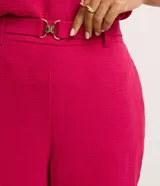 Pantalón zanahoria color fucsia de tiro alto, confeccionado en tejido airflow, con cintura elastizada, trabillas y hebillas metálicas.