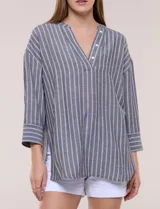 Blusa de silueta holgada a rayas verdes y blancas, confeccionada en tela liviana con textura arrugada. Presenta cuello en V profundo con botones frontales, mangas 3/4 de hombro caído y ruedo asimétrico con aberturas laterales.