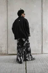 Campera unisex de cuello alto con cierre frontal completo. Presenta un diseño de paneles con efecto de lavado ácido en tonos negro y gris, corte relajado y bolsillos laterales.