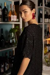 Vestido corto de punto con acabado brillante de lurex y textura de trenzas. Presenta cuello redondo, mangas cortas abullonadas y ruedos con terminación ondulada. De corte holgado y diseño versátil.