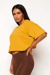 Remera corta de manga corta color celeste, con escote amplio en la espalda que se anuda en la parte inferior, dejando ver un top deportivo amarillo con tiras cruzadas.