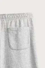 Pantalón jogger de corte relajado y pernera ancha, confeccionado en tejido de algodón con interior perchado. Cuenta con cintura elástica ajustable mediante cordón interior, bolsillos laterales y un bolsillo trasero de plastrón.