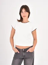 Remera de corte ajustado en color blanco, con cuello redondo y bordes en contraste color negro en el cuello y las mangas.