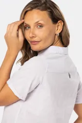 Camisa de lino de manga corta con cuello camisero, cierre frontal de medio botón con botones metálicos personalizados y dos bolsillos en el pecho.