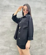 Camisa negra de manga larga con botones dorados, corte holgado y cuello clásico. Ideal para usar abierta sobre un top o cerrada como prenda principal.