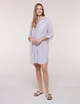 Vestido camisero corto con estampado a rayas verticales en color marrón y blanco, de cuello camisero con escote en V y botones frontales parciales. Cuenta con bolsillos laterales y en el pecho, mangas largas con presillas para ajustar y ruedo curvo asimétrico.