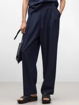 Pantalón de vestir azul marino, de corte recto, con bolsillos laterales y traseros. Se ajusta a la cintura con cinturón de cuero marrón.