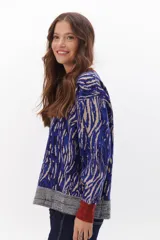 Sweater de punto con estampado animal print en tonos marrones, negros y blancos. Tiene cuello redondo, puños y bajo acanalados en color marrón y gris.