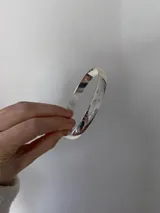 Pulsera tipo esclava rígida de diseño ancho y superficie lisa con acabado brillante.