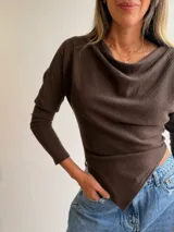 Tejido de punto color chocolate, con diseño asimétrico, cuello tipo buche y mangas largas. Presenta una caída suave con un corte en pico en el ruedo.