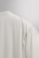 Camiseta de entrenamiento regular fit color beige, confeccionada en combinación de tejidos técnicos ligeros y elásticos con tecnología Quick Dry nivel 2. Presenta cuello redondo, manga corta, acabados con costuras planas y termofijadas, y detalle de logo estampado en el bajo.