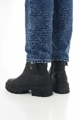 Botinetas de cuero negro con suela track y taco bajo. Presentan una correa decorativa con hebilla metálica alrededor del tobillo y cierre lateral interno.