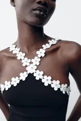 Body negro de tejido elástico con escote halter y detalle de flores blancas aplicadas en el contorno.