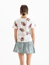 Remera blanca de manga corta y cuello redondo, con estampado de peras en tonos rosados y verdes.
