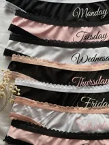 Pack de siete bombachas tipo less de seda fría, cada una con el estampado correspondiente a un día de la semana y detalles de encaje en la cintura.