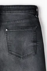 Pantalón jean de cinco bolsillos en denim de algodón con lavado negro y efecto deslavado. Presenta un corte regular de pierna recta y tiro medio con cierre frontal de botón y cremallera.
