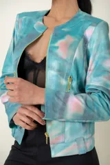 Campera de cuero sintético estampada con diseño abstracto en tonos celeste, rosa y gris. Cierre frontal y bolsillos laterales con cremalleras doradas.