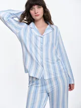 Camisa de pijama de manga larga con cuello solapa y cierre frontal de botones. Presenta un estampado sutil de pequeños corazones sobre una base de color gris melange, con detalles de ribete en contraste en el cuello y la botonera.